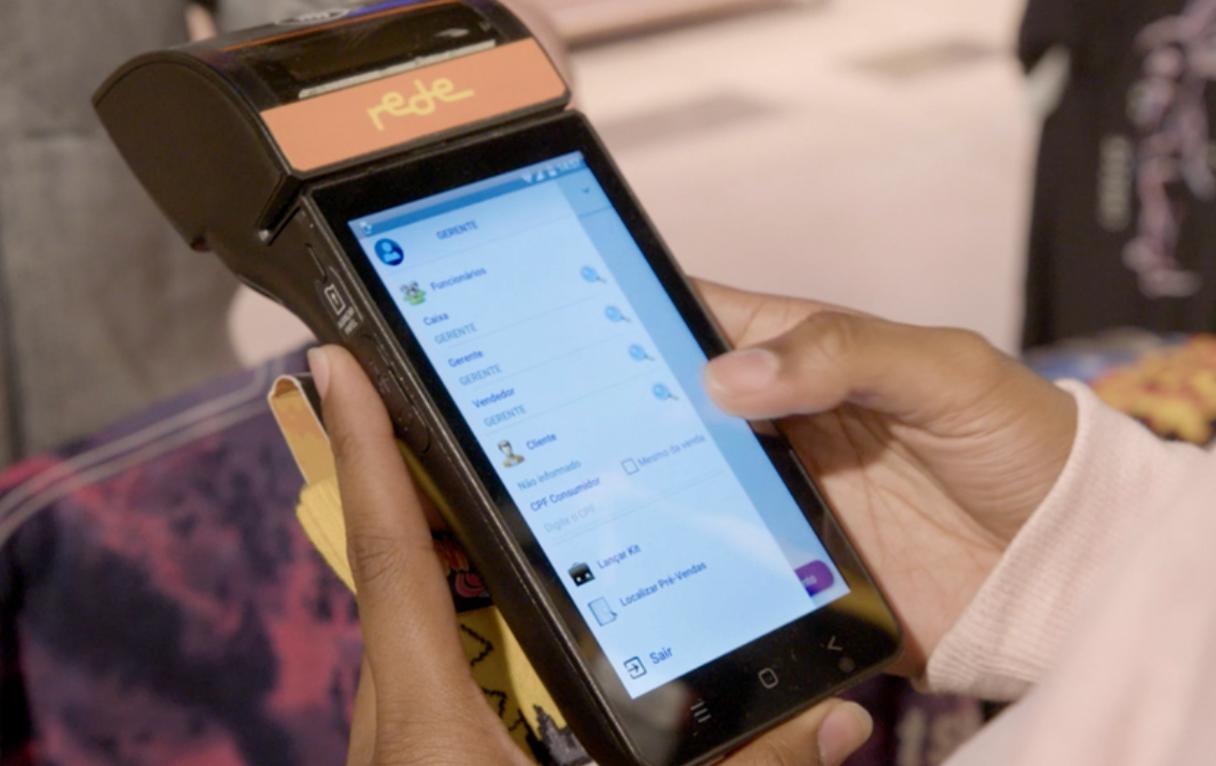 Vendedor utilizando o Presence Sale em uma maquininha smart POS no salão da loja